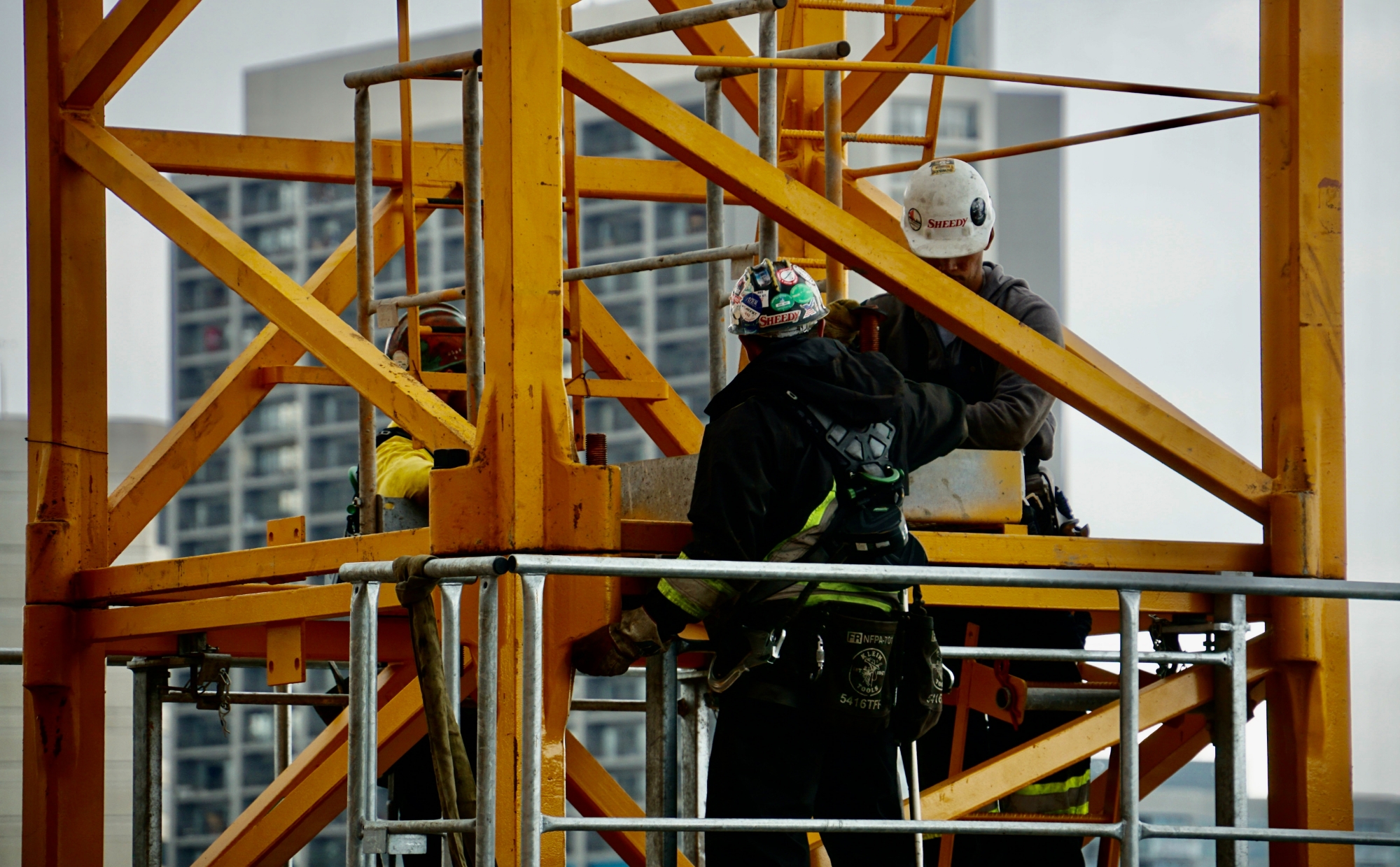 Three construction workers, working on a metal structure